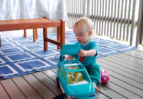 Elsa playing with a Barbie car on our deck