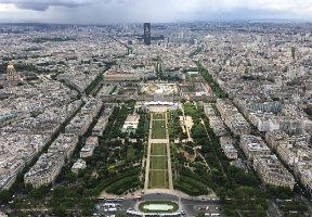 Champs de Mars and Tour Montparnasse in the background, with rain clouds approaching. The tower has a large "Paris 2024 Olympics" symbol, and at the time of taking this picture Paris had not yet been awarded the 24 olympics.